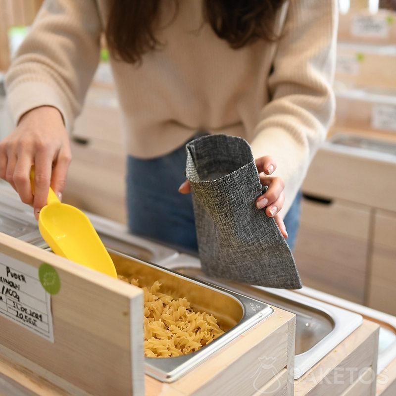 Vrouw winkelt door bulkproducten in duurzame boodschappenzakjes te doen - herbruikbare jute verpakking