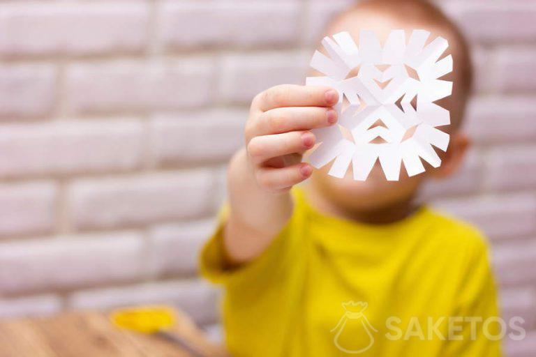 Kind knipt een sneeuwvlok uit papier