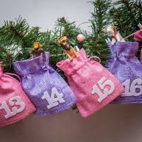 Een adventskalender van jute zakjes 12 x 15 cm roos en paars + witte nummers Jute zakjes