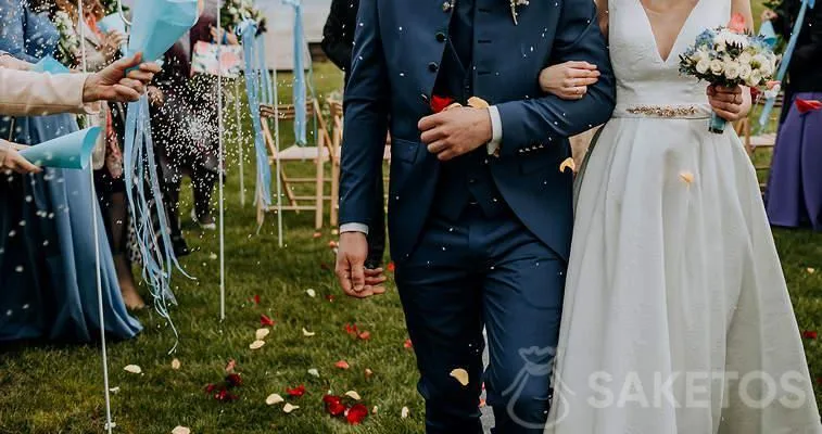 Het bruidspaar overladen met rozenblaadjes en rijst