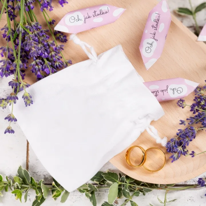 Elegant wit satijnen zakje voor trouwbedankjes bij gouden trouwringen.